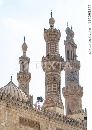 Al-Azhar Mosque in Cairo features intricate architecture with tall minarets and a domed roof. The structure showcases Islamic design elements and historical significance. Al-Azhar Mosque in Cairo features intricate architecture with tall minarets and a domed roof. The structure showcases Islamic design elements and historical significance. 136095865