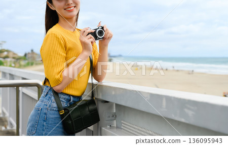 一位女士帶著相機在美麗的海邊 136095943