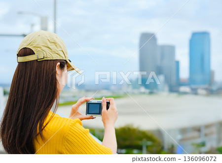 A woman photographs a fantasy city with a camera A woman photographs a fantasy city with a camera 136096072