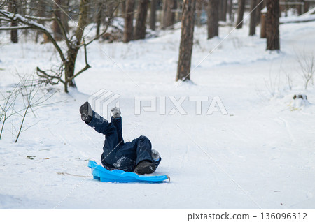 Little boy enjoying winter outdoor fun while sledding in snowy forest. Active childhood, seasonal outdoor recreation, winter adventure, family leisure and healthy lifestyle concept Little boy enjoying winter outdoor fun while sledding in snowy forest. Active childhood, seasonal outdoor recreation, winter adventure, family leisure and healthy lifestyle concept 136096312