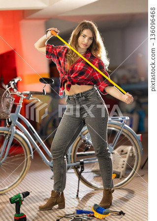 Young woman confidently holding measuring tape in workshop Young woman confidently holding measuring tape in workshop 136096468