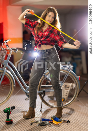 Woman holding measuring tape near bicycle workshop tools Woman holding measuring tape near bicycle workshop tools 136096469