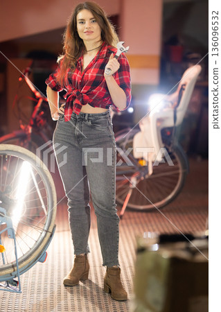 Young woman mechanic holding wrench in bicycle repair shop Young woman mechanic holding wrench in bicycle repair shop 136096532