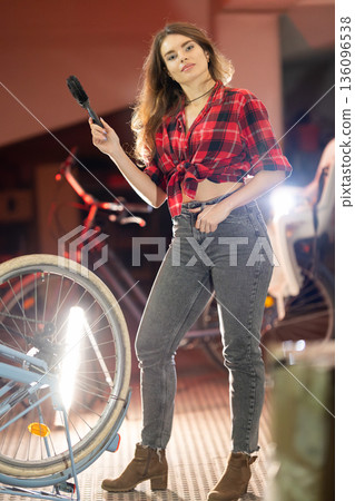 Young woman repairing bicycle wheel in workshop 136096538
