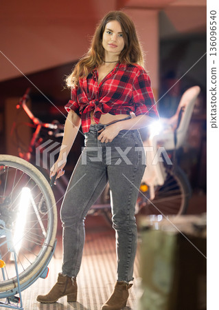 Young woman repairing bicycle tire in workshop 136096540