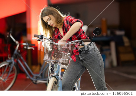 Young woman adjusting bicycle basket in garage 136096561
