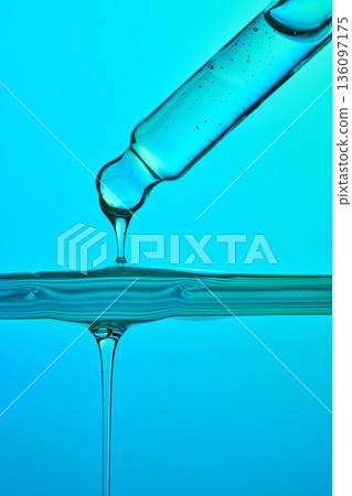 Serum dropper dispensing liquid on blue background Serum dropper dispensing liquid on blue background 136097175