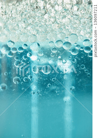 Blue liquid creating an abstract texture with transparent bubbles forming on the surface 136097211