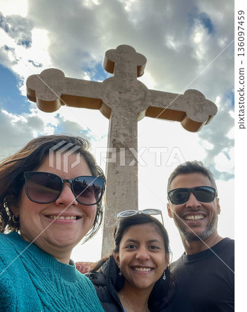 A woman, a man and a child are smiling for a picture in front of a cross A woman, a man and a child are smiling for a picture in front of a cross 136097459