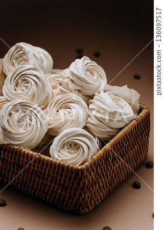 White meringue rosettes in wicker basket with coffee beans, beige copy space 136097517