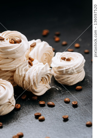 Coffee bean topped meringue cookies on dark slate with copy space 136097520