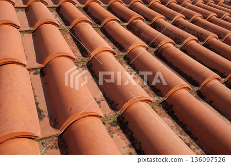 Terracotta roof tiles in warm sunlight, repeating curved shapes and textures. Mediterranean architecture background with natural aging and geometric pattern. Terracotta roof tiles in warm sunlight, repeating curved shapes and textures. Mediterranean architecture background with natural aging and geometric pattern. 136097526