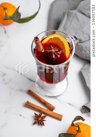 Glass of mulled wine, orange, cinnamon, and star anise on a marble background with spice Glass of mulled wine, orange, cinnamon, and star anise on a marble background with spice 136097583