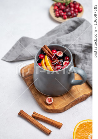 A cup of red mulled wine with cinnamon, orange and cranberry on a wooden board A cup of red mulled wine with cinnamon, orange and cranberry on a wooden board 136097585