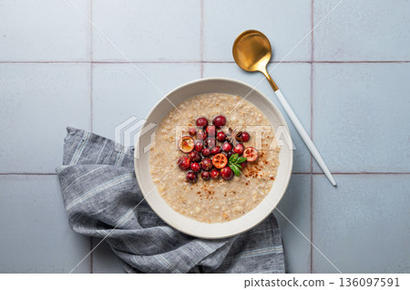 Oatmeal with cranberry, cinnamon and spicy in a plate on a blue tile background Oatmeal with cranberry, cinnamon and spicy in a plate on a blue tile background 136097591
