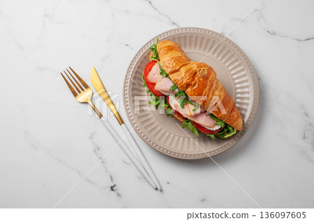 Croissant sandwich with ham, mozarella cheese and arugula on a plate on a marble background Croissant sandwich with ham, mozarella cheese and arugula on a plate on a marble background 136097605