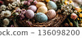 A basket holds bright Easter eggs placed on soft moss. Around the basket, there are flowers and green plants in pots, showing signs of springtime, banner 136098200