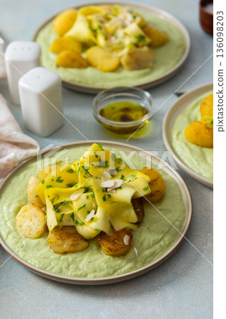 Baked potatoes are topped with slices of fermented zucchini and served alongside a green pea sauce with broccoli. This meal is prepared for a healthy breakfast Baked potatoes are topped with slices of fermented zucchini and served alongside a green pea sauce with broccoli. This meal is prepared for a healthy breakfast 136098203
