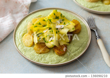 Baked potatoes are topped with slices of fermented zucchini and served alongside a green pea sauce with broccoli. This meal is prepared for a healthy breakfast Baked potatoes are topped with slices of fermented zucchini and served alongside a green pea sauce with broccoli. This meal is prepared for a healthy breakfast 136098210