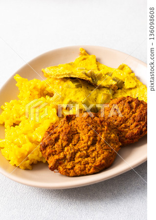Colorful bowl of rice with rhubarb fried eggs, baked sweet potato, cauliflower, zucchini, and meat fritters alongside a fresh salad. Enjoy a nutritious and flavorful meal 136098608