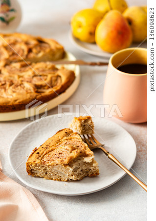A slice of pear pie sits on a white plate with a fork. A warm coffee cup is next to it. Fresh pears are placed on the table, adding to the scene A slice of pear pie sits on a white plate with a fork. A warm coffee cup is next to it. Fresh pears are placed on the table, adding to the scene 136098623
