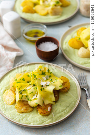 Baked potatoes are topped with slices of fermented zucchini and served alongside a green pea sauce with broccoli. This meal is prepared for a healthy breakfast Baked potatoes are topped with slices of fermented zucchini and served alongside a green pea sauce with broccoli. This meal is prepared for a healthy breakfast 136098641