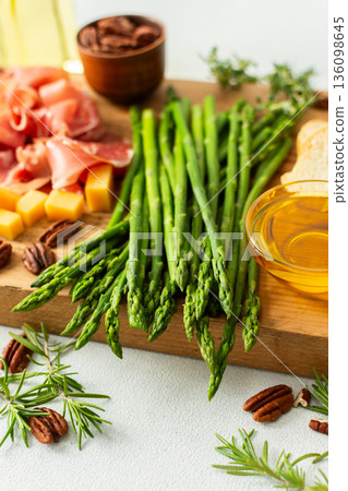 Indulge in a beautifully arranged charcuterie board with vibrant asparagus, savory cured meats, assorted cheeses, and freshly toasted bread, ideal for sharing with friends Indulge in a beautifully arranged charcuterie board with vibrant asparagus, savory cured meats, assorted cheeses, and freshly toasted bread, ideal for sharing with friends 136098645