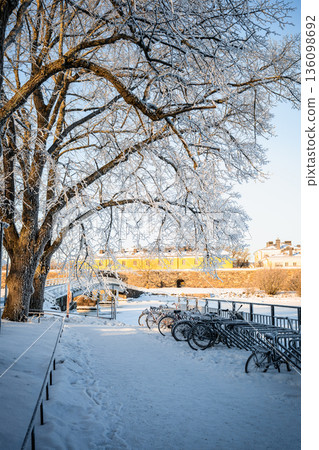 Snowy winter cityscape with bicycles under frosty tree near Finnish fortress in sunlight Snowy winter cityscape with bicycles under frosty tree near Finnish fortress in sunlight 136098692