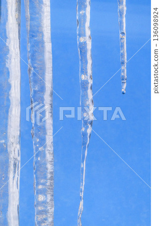 Icicles hanging from the roof in Morioka City, Iwate Prefecture. The blue winter sky and melting icicles signal spring is near. 136098924