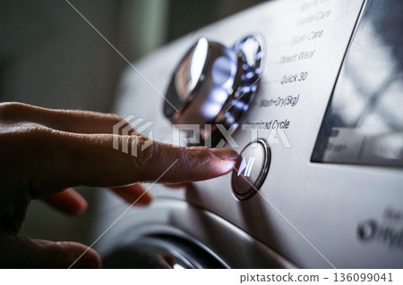 Washing machine, smart home appliances. Pressing start button on modern washing machine display. Daily chores, close-up shot Washing machine, smart home appliances. Pressing start button on modern washing machine display. Daily chores, close-up shot 136099041