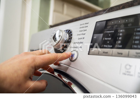 Washing machine, smart home appliances. Pressing start button on modern washing machine display. Daily chores, close-up shot Washing machine, smart home appliances. Pressing start button on modern washing machine display. Daily chores, close-up shot 136099043