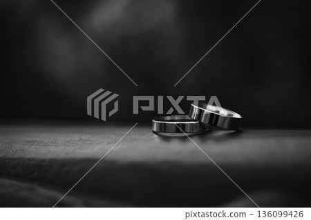 Two metal wedding rings on dark fabric surface with black background Two metal wedding rings on dark fabric surface with black background 136099426