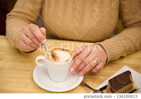 Cozy Cafe Moment: Person Stirring Cappuccino With Chocolate Cake Nearby Cozy Cafe Moment: Person Stirring Cappuccino With Chocolate Cake Nearby 136100815