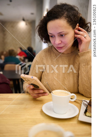 Woman In Cozy Sweater Using Phone In Cafe With Coffee And Cake 136100823