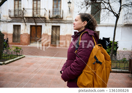Woman With Burgundy Jacket And Yellow Backpack Standing On City Street Photo Woman With Burgundy Jacket And Yellow Backpack Standing On City Street Photo 136100826