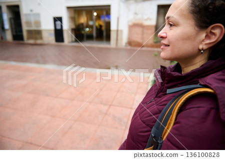 Profile Of A Woman In A Maroon Jacket With Backpack On A Quiet City Street Profile Of A Woman In A Maroon Jacket With Backpack On A Quiet City Street 136100828