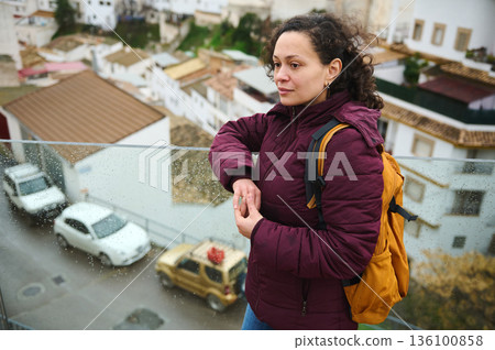 Contemplative Woman With Backpack On Rainy Balcony Overlooking an Urban Neighborhood Contemplative Woman With Backpack On Rainy Balcony Overlooking an Urban Neighborhood 136100858