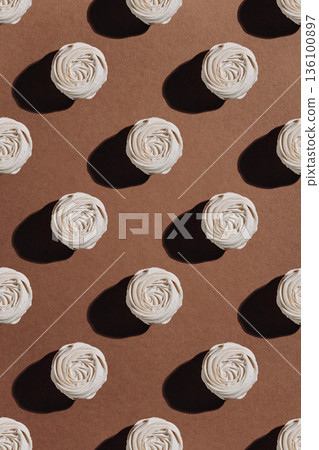 White meringue rosettes pattern on brown kraft paper with hard sunlight shadows White meringue rosettes pattern on brown kraft paper with hard sunlight shadows 136100897