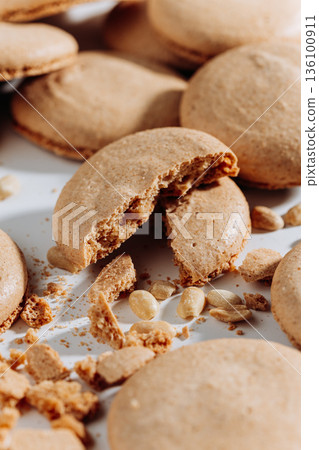 Broken peanut macarons with crumbs and nuts on white background, close up 136100911