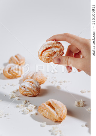 Hand holding powdered sugar pastry with crumbs on white background Hand holding powdered sugar pastry with crumbs on white background 136100912