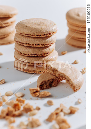 Stacked peanut macarons with bitten cookie and crumbs on white background Stacked peanut macarons with bitten cookie and crumbs on white background 136100916