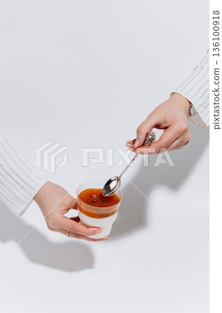 Hands tasting panna cotta with passion fruit topping on white background 136100918