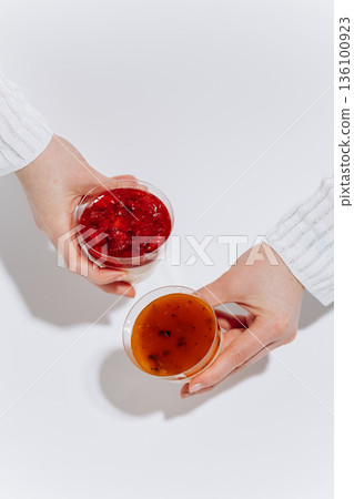 Hands holding two panna cotta cups with berry and passion fruit topping Hands holding two panna cotta cups with berry and passion fruit topping 136100923