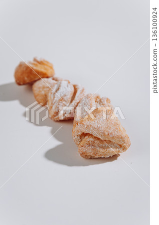 Powdered sugar pastries close-up on white background, soft shadows Powdered sugar pastries close-up on white background, soft shadows 136100924