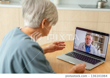 Senior man doctor expert examining older senior woman online. Old woman lady patient and doctor talk on video call have consultation with laptop. Medicine healthcare medical checkup. Online doctor 136101064