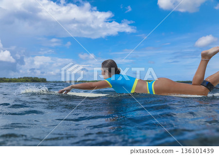Athletic female surfer Amidst Scattered Clouds From Ocean Perspective Athletic female surfer Amidst Scattered Clouds From Ocean Perspective 136101439