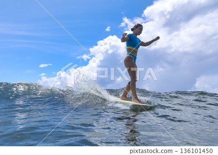 Woman Standing Proudly On Surfboard Amidst Turbulent Cloudy Backdrop Woman Standing Proudly On Surfboard Amidst Turbulent Cloudy Backdrop 136101450