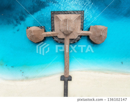 Aerial top down view of sea and wooden pier with thatched roof Aerial top down view of sea and wooden pier with thatched roof 136102147