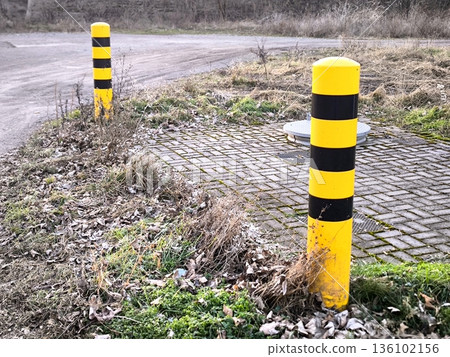 Yellow and black warning posts on the side of the road 136102156