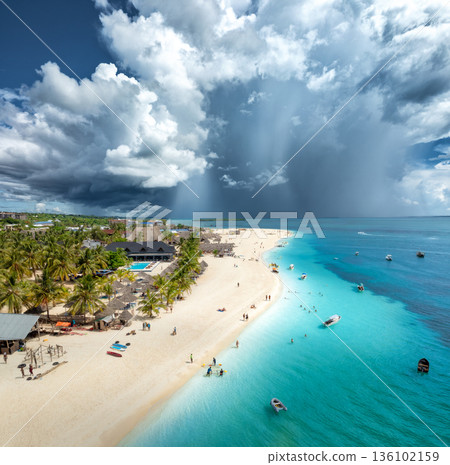 Aerial view of tropical sandy beach, blue sea and rain clouds Aerial view of tropical sandy beach, blue sea and rain clouds 136102159